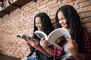 Two teens reading a book each
